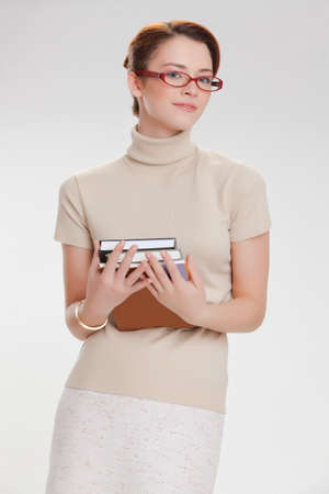 beautiful girl with books and wearing glasses in a beige jacketの写真素材
