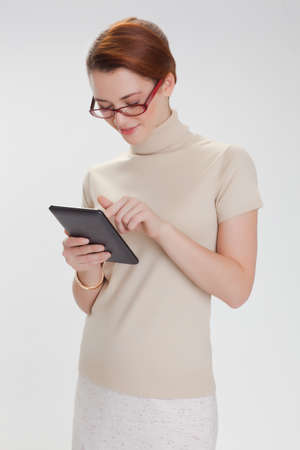 beautiful woman in a beige sweater with tablet computer isolated white backgroundの写真素材
