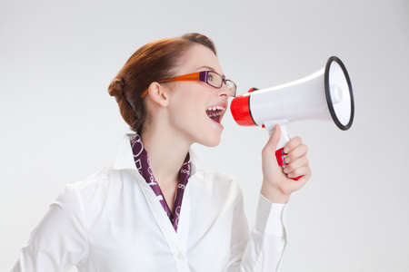 business woman is screaming to her associate with megafon  isolated white backgroundの写真素材