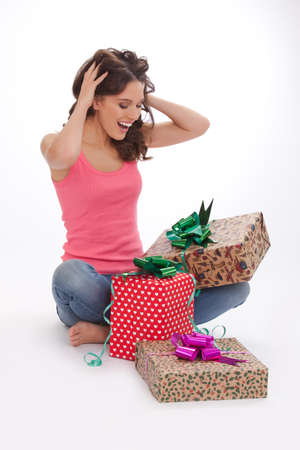 What surprise. Surprised young woman in a red t-shirt and blue jeans s opening gift box and smiling while standing on white backgroundの写真素材