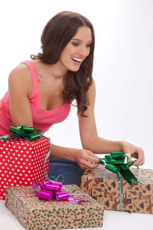 What surprise. Surprised young woman in a red t-shirt and blue jeans s opening gift box and smiling while standing on white backgroundの写真素材