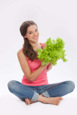 beautiful girl in red shirt and blue jeans holding a fresh salad leavesの写真素材