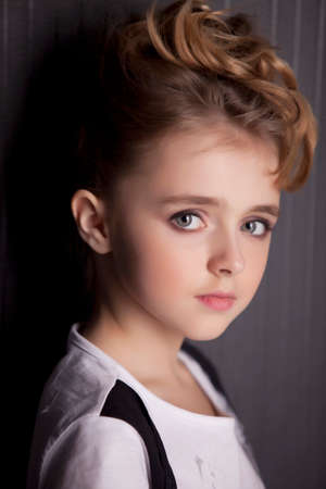 Style teen girl with backpack standing near black wall.の写真素材