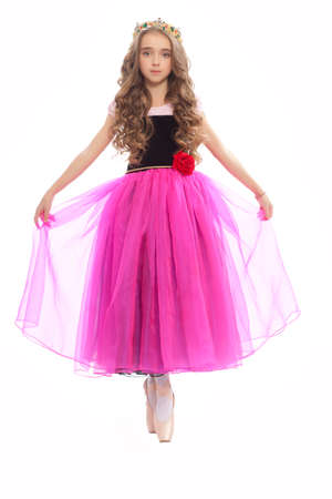 Beautiful young female classical ballet dancer on pointe shoes wearingblack leotard pink stockings and purple dress isolated on white studio background in the crownの写真素材