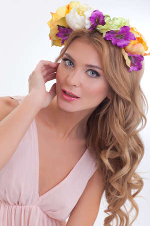 beautiful girl with long blond hair in beige dress with a wreath of flowers on her headの写真素材