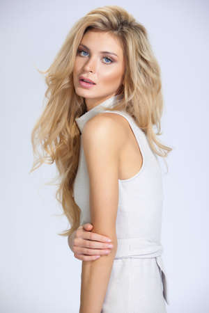 beautiful woman with long hair in beige dress on white backgroundの写真素材