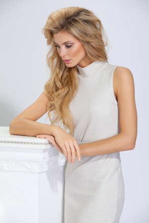 beautiful woman with long hair in beige dress on white backgroundの写真素材