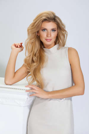 beautiful woman with long hair in beige dress on white backgroundの写真素材