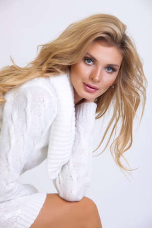 girl in a white knitted dress with long hair on a white backgroundの写真素材
