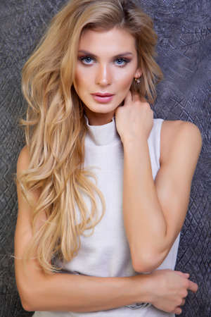 beautiful woman with long hair in beige dress  next to the dark wallの写真素材