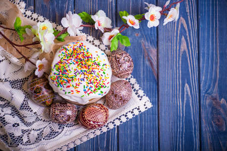 traditional easter cake kulich Ukrainian Russian with colored eggs on blue wooden background