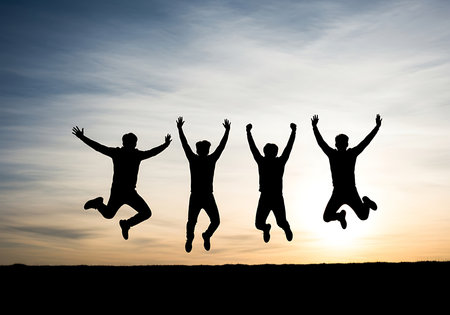 Silhouette of a group of people jumping in the air at sunsetの素材