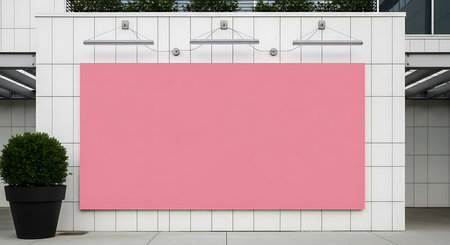 A large blank pink advertising board is mounted on a modern white tiled wall outdoors, accompanied by a potted green plant and three sleek outdoor lights, creating a clean, contemporary atmosphere ideal for promotional content and commercial use.の素材