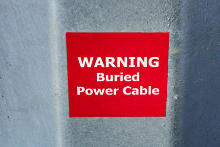 Warning Buried Power Cable Sign on Metal Pole.の写真素材