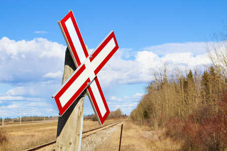Railroad crossing sign along gravel road.の写真素材