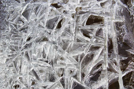 Ice crystals formed on the edge of running water with a black background.