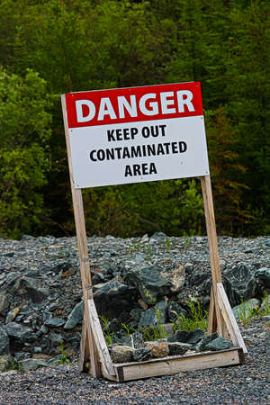 A danger keep out of contaminated area sign on rocky ground.の写真素材