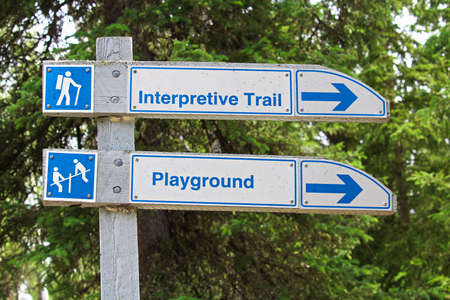 A direction sign for an interpretive trail and playground.