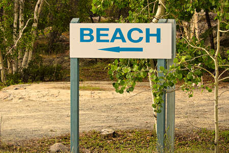 A blue beach sign with a direction arrow.の写真素材