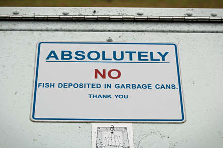 Absolutely no fish deposited in garbage can sign.の写真素材