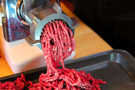 Closeup of meat coming out of a meat grinder.の写真素材