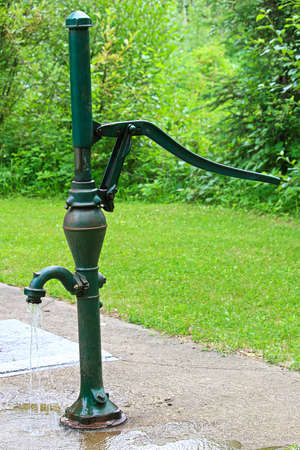 An old fashion hand pump pouring water.
