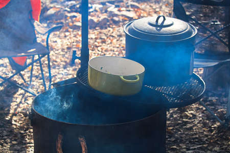 Two pots sitting on grill over a campfire.の写真素材