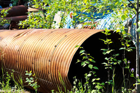 A rusty culvert laying in a scape metal yard.