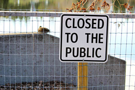 A lakeside path with a closed to the public sign.