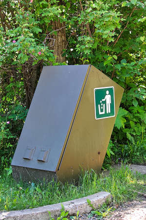 A bear proof waste container beside some trees.の写真素材