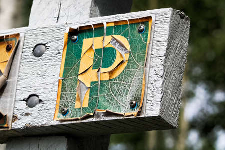 A faded peeling parking sign on wood.の写真素材