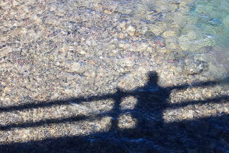 Shadow of an individual on a bridge looking at the water