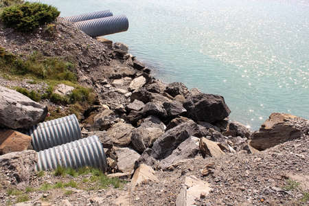 Four culverts next to a body of waterの写真素材