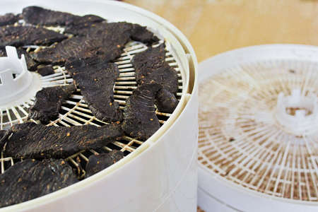Jerky slices with empty dehydrator trays in the background.