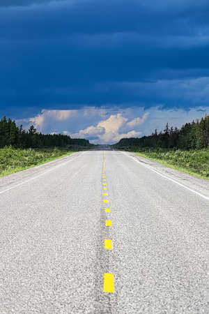 The long view of a highway with a storm brewing in the distanceの写真素材