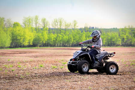 A young boy quading in a spring field.