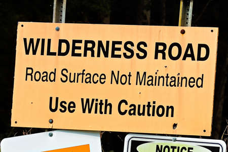 An orange wilderness road, use with caution sign