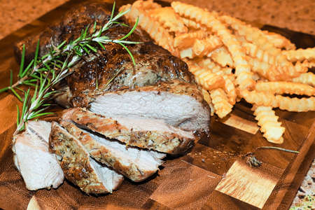A lamb roast on a wooden board with crinkled fries.の写真素材