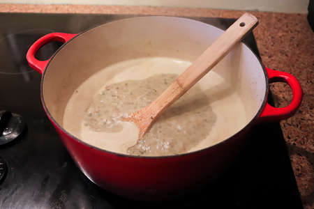A pot of cream based broth cooking on the stoveの写真素材