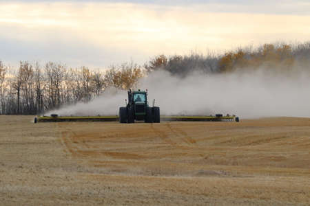BONNYVILLE, ALBERTA, CANADA - SEPTEMBER 10, 2020: A local farmer in John Deere tractor works infront of a cloud of dust as he levels a harvested fieldのeditorial素材