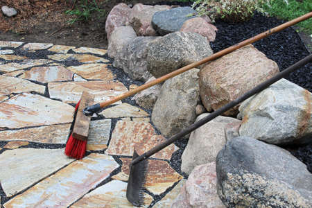 A rake and broom used on patio stonesの写真素材