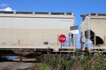 A train speeds past a stop sign at a crossingの写真素材