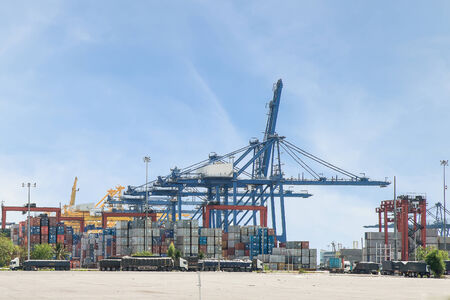 Industrial Container Cargo with working crane bridge in shipyard with nice sky for Logistic Import...