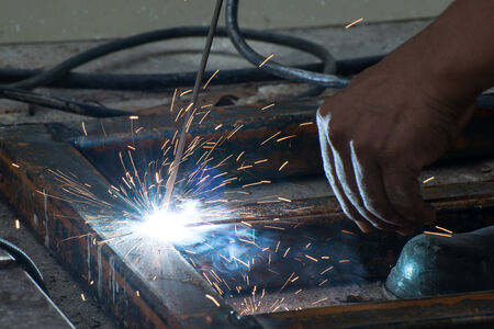Worker welding steel with sparks lightingの写真素材