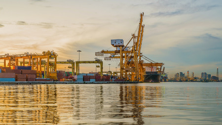 Industrial Container Cargo freight ship with working crane bridge in shipyard at dusk for Logistic Import Export backgroundのeditorial素材