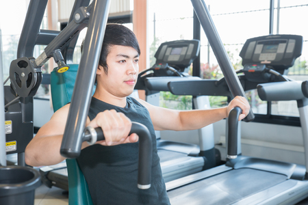 Fit man exercising at the gym on a machineの写真素材