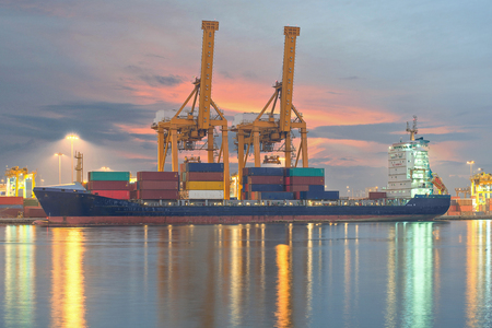 Container Cargo freight ship with working crane bridge in shipyard at dusk for Logistic Import Export backgroundの写真素材