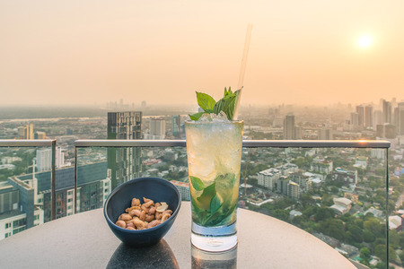 Mojito cocktail and cashews on table in rooftop barの写真素材