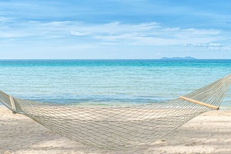 Summer, Travel, Vacation and Holiday concept - Empty hammock between palm trees on tropical beachの写真素材