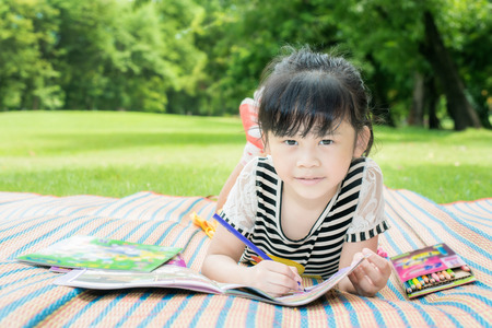 Young girl outdoors lying on the grass and drawingの写真素材